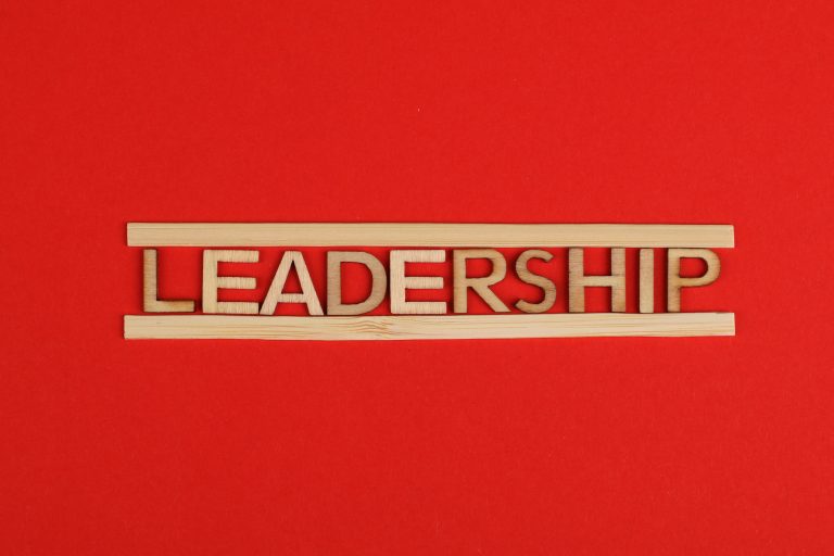 Wooden letters spelling leadership on a vibrant red background, conveying bold concepts.